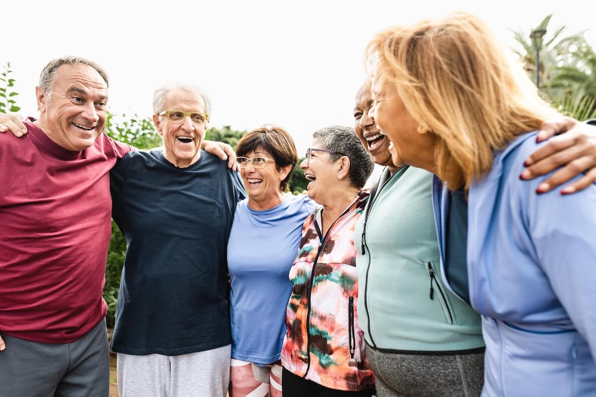 Picture featuring a group of smiling older adults hugging each other.