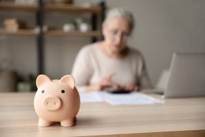 Older woman going through her finances and a piggy bank