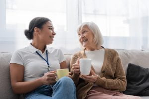 Older woman with a caregiver drinking tea together