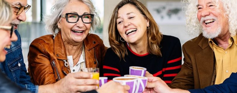 Senior group of retired people celebrating while having breakfast together at cafe bar.