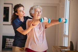 Caregiver helping an older woman exercise.